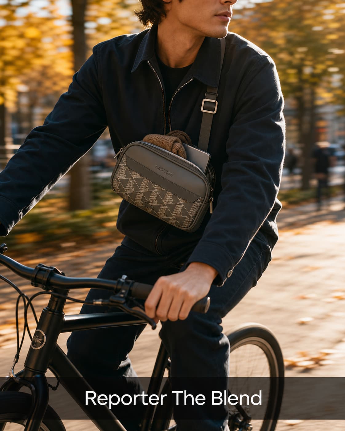 Un jeune professionnel à vélo avec un sac reporter Lacoste The Blend en bandoulière, bien rempli avec un pull roulé et une tablette dépassant, dans un parc urbain aux couleurs automnales, avec un éclairage de dos créant un liseré lumineux et un bandeau semi-transparent en bas indiquant 