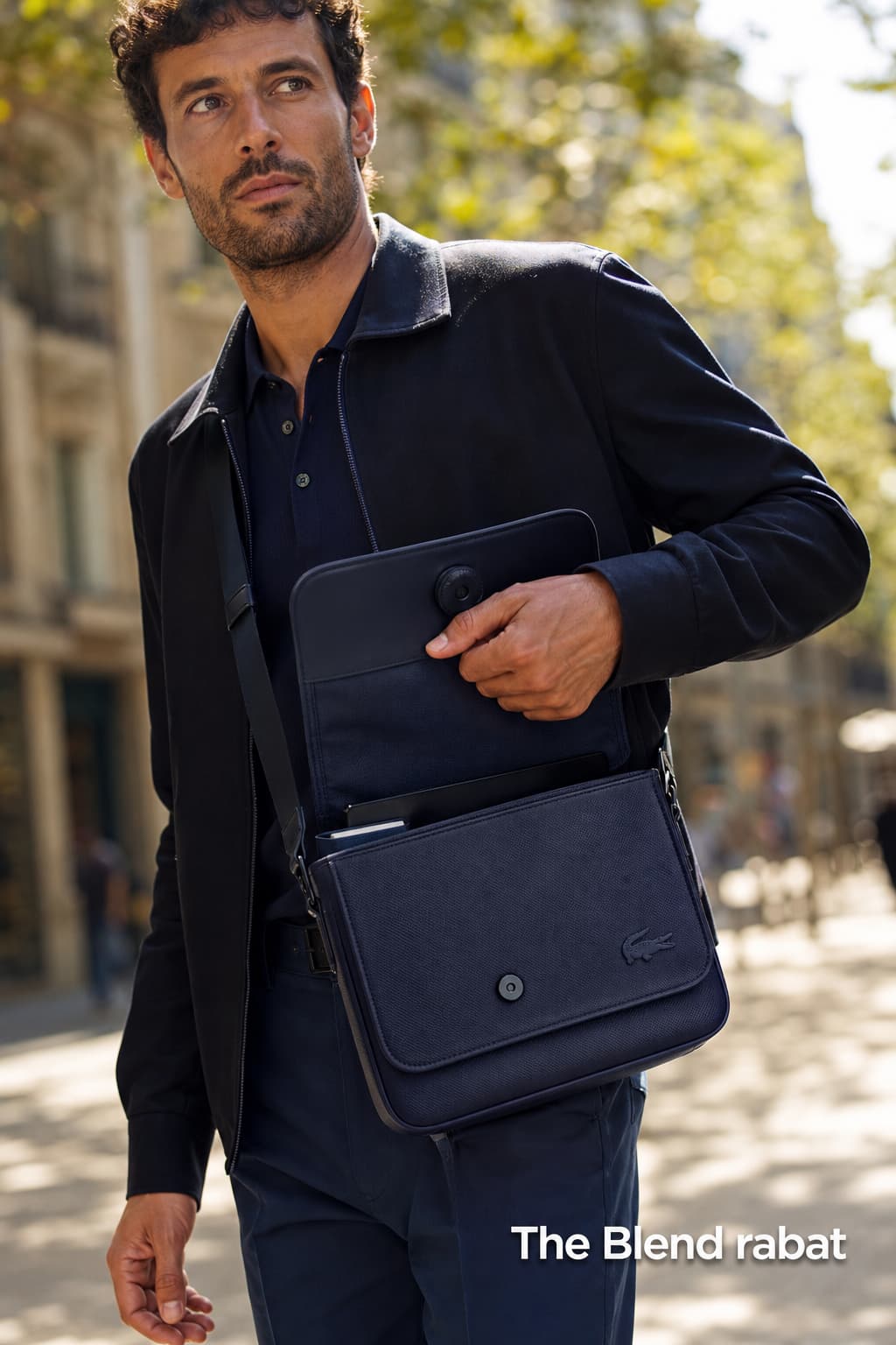 Un homme en tenue décontractée-chic portant une sacoche Lacoste 