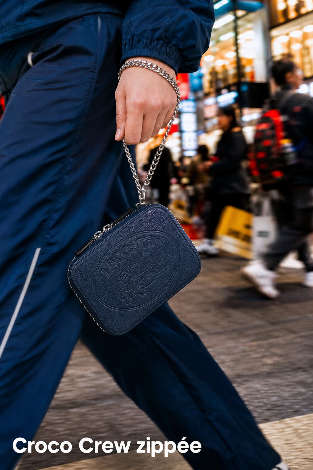 Pochette zippée Lacoste Croco Crew en cuir grainé suspendue au poignet d