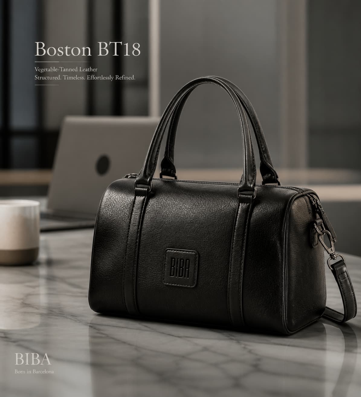 Sac structuré BIBA Boston BT18 en cuir noir posé sur une surface en marbre dans un bureau moderne avec un ordinateur portable et une tasse de café en arrière-plan.