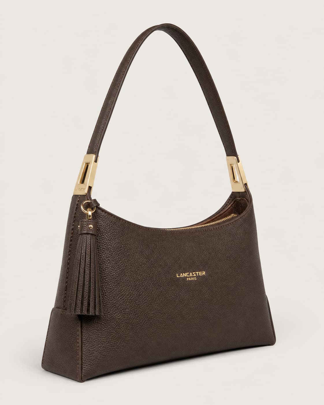 Sac à main Lancaster Lychee Ace en cuir grainé marron foncé, vu de trois quarts, avec fermeture éclair et pompon, sur fond neutre.