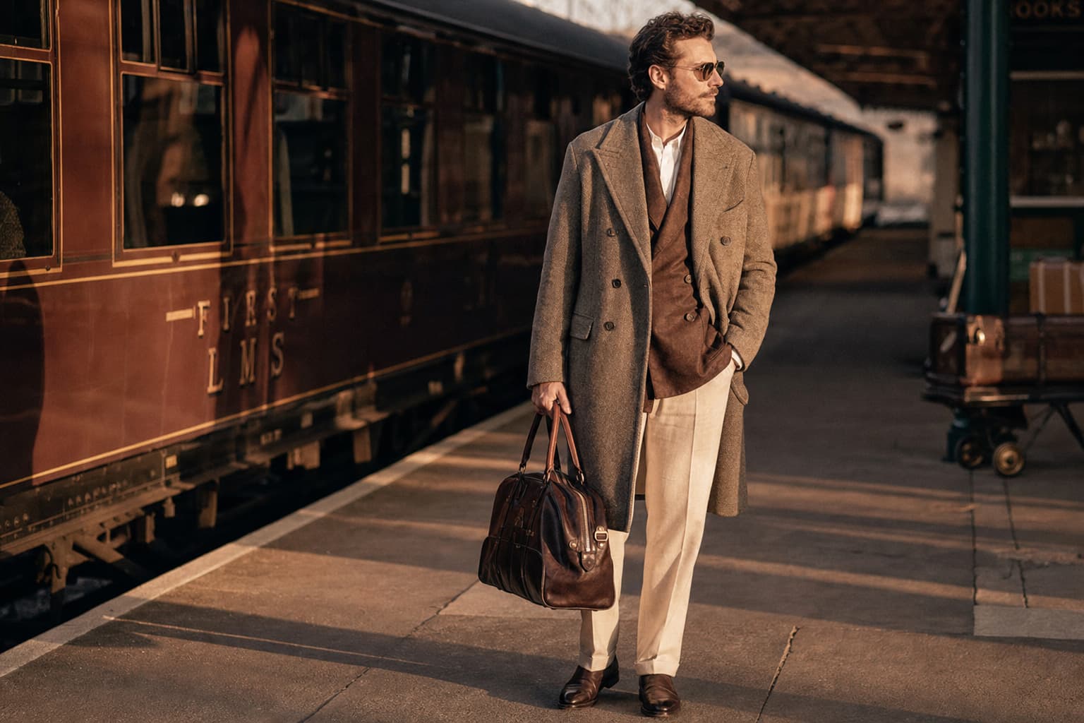 Un voyageur chic tenant un sac de voyage en cuir vintage sur un quai de gare à l